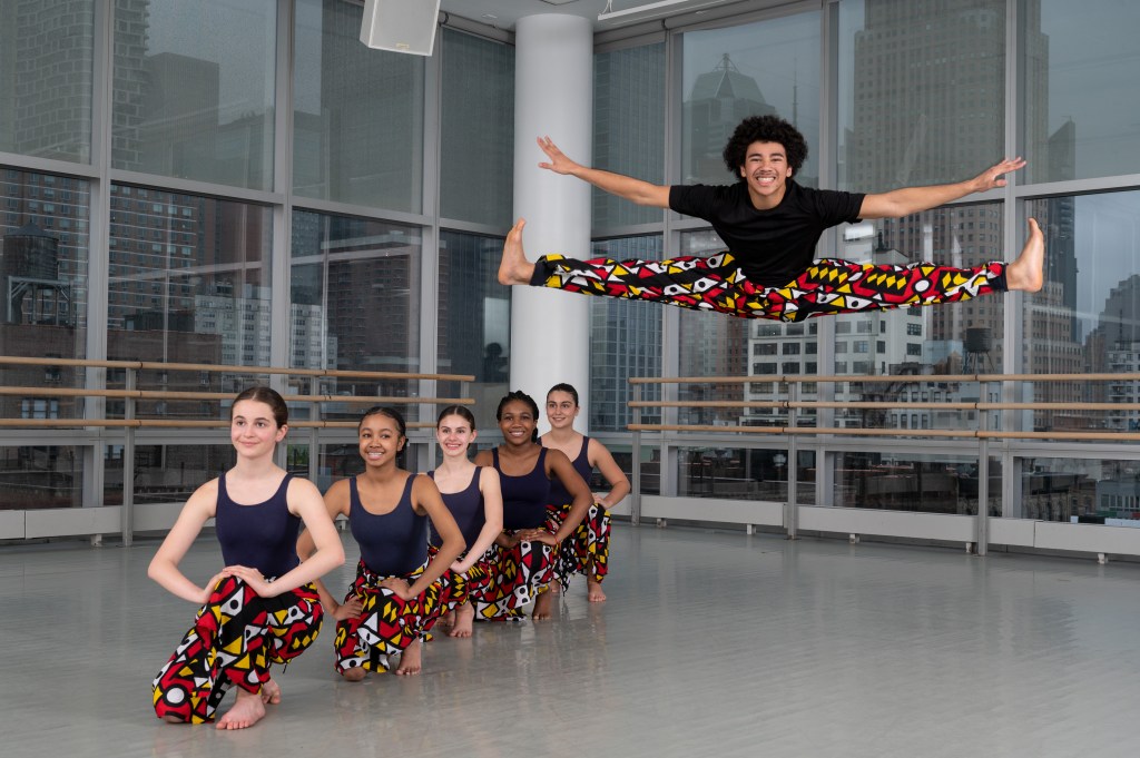 Students from The Ailey School's Junior Division. One student is in the air doing the splits.